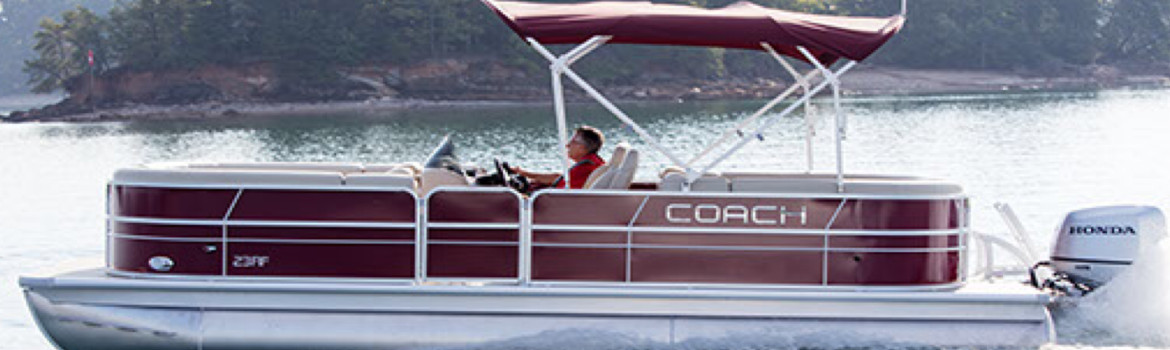 A man cruising on a Coach Pontoon II RFC pontoon near the shore of a forest.