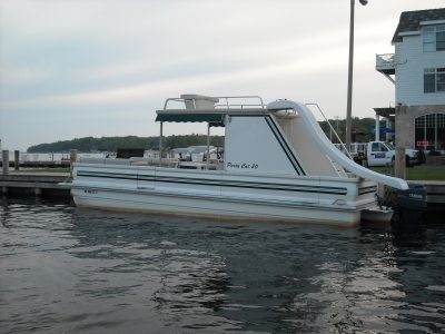 A white pontoon boat afloat at the harbor in the early morning.
